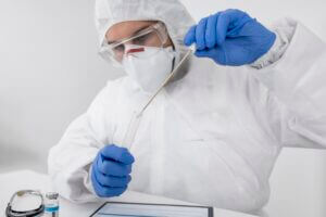 doctor wearing face mask and surgical gloves performing test in a test tube