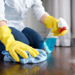 A girl using surface disinfectants to clean the floor