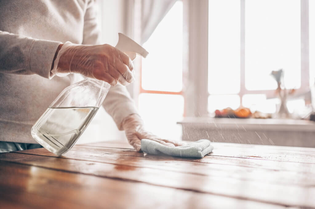 Image of a person using EN 14476 certified surface sanitizer to sanitize the table top