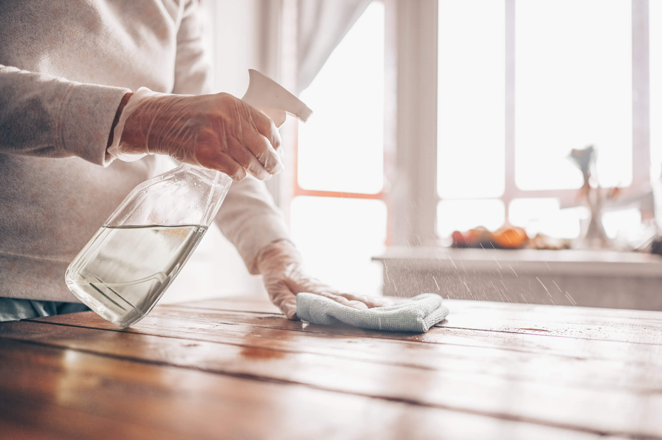 Image of a person using EN 14476 certified surface sanitizer to sanitize the table top