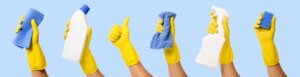 hands with gloves holding cleaning products