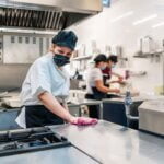female cook disinfecting her kitchen after work in food service sector