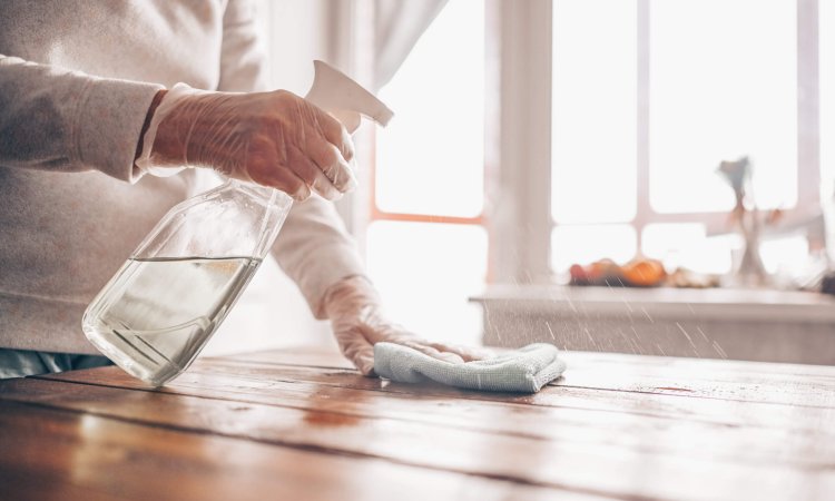 Image of a person using EN 14476 certified surface sanitizer to sanitize the table top