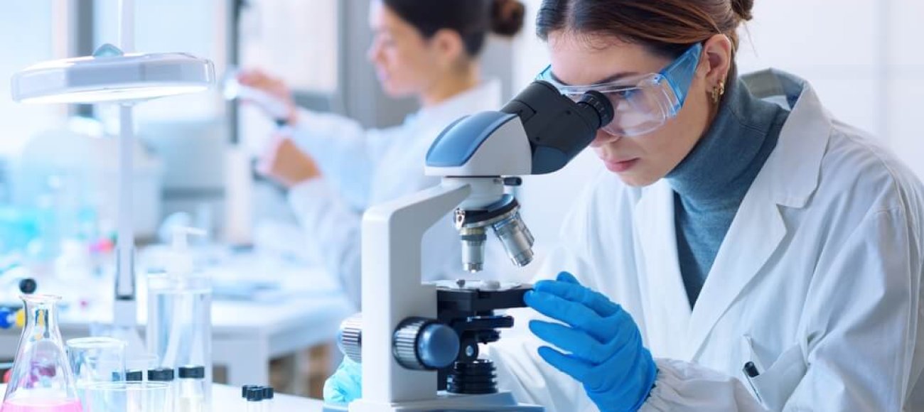 The image describes a lab technician performing biocidal product testing using a microscope to enumerate the viable spores.